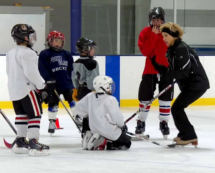 Suzy demonstrating skating technique to a small group of hockey players
