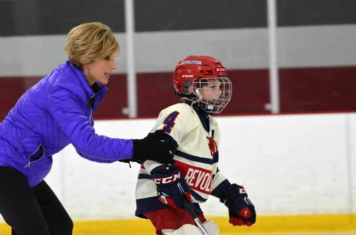 Suzy guiding a young hockey player during skating practice