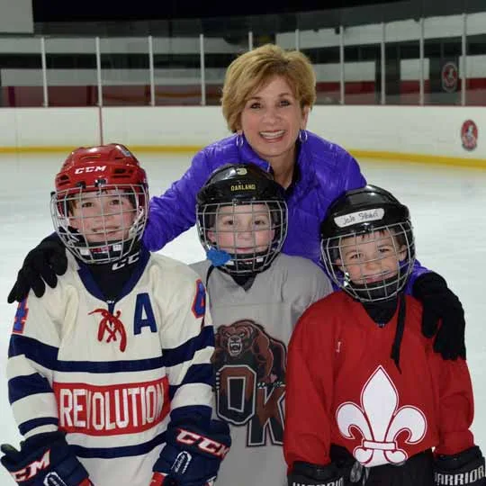 Suzy with three young hockey players at the rink